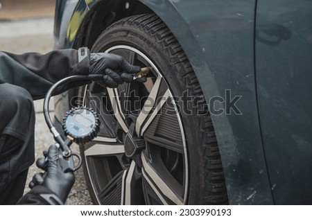 worker checking the air pressure of a cars tyre using a handheld device