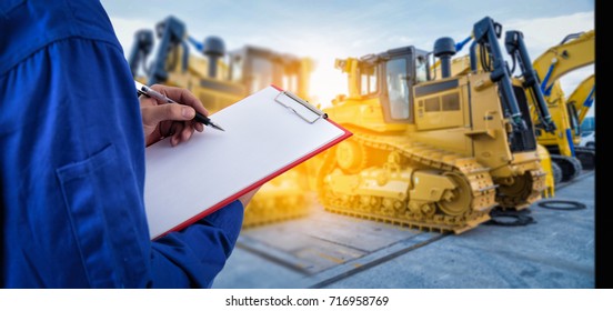 Worker checking document in front of the mechanical excavator at yard  for import export business.