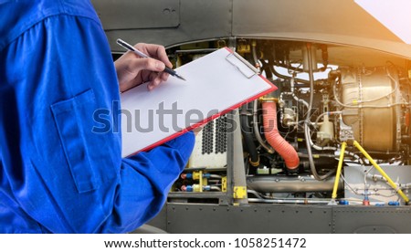 Worker checking document in front of the the parth of fighter plane is background.