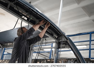 Worker checking and installing electrical cables inside an RV. Professional wiring, inspection, and installation process during motorhome construction or repair.