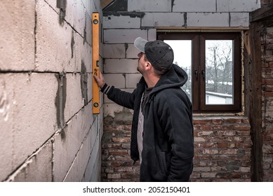 Worker Checking Level Of The Wall With The Water Level Tool