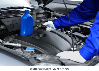 Worker checking motor oil level in car, closeup