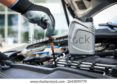 Worker checking motor oil level in car with dipstick, closeup
