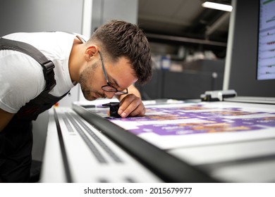 Worker checking print quality of graphics in modern printing house. - Shutterstock ID 2015679977