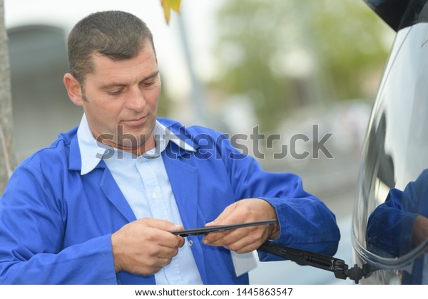 worker\
checking rear windscreen wiper blade on\
car