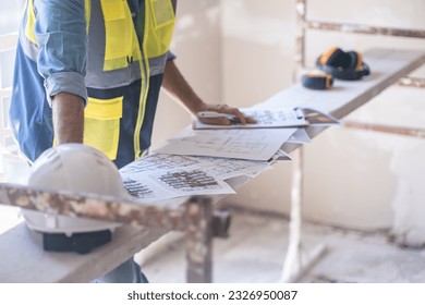 Worker checking renovation project papers put on construction equipment near helmet man in professional uniform doing paperwork before reconstruction process in apartment - Shutterstock ID 2326950087