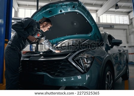 Worker checking technical condition of car engine