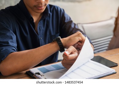 Worker Checking Time And Looking At Wrist Watch At Home Office. Young Businessman Seeing Clock To Work. On Desk With Calendar, Annual, And Summary Report.Time Out For Appointment Meeting Concept.