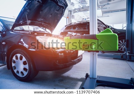 Worker checks and adjusts the headlights of a car's lighting system. Auto repair service.
