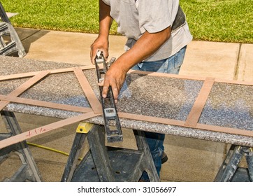 A Worker Checks The Size Of A Granite Slab For Use In A Suburban Home Kitchen Remodel