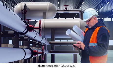 Worker In Chemical Plant. Engineer Next To Pipeline. Man Looks At Tablet. Working In Chemical Factory. Engineer Inside Chemical Factory Building. Guy Stands In Front Of Pipelines. Industrial Career