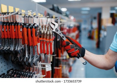 Worker choosing adjustable wrench in tool store