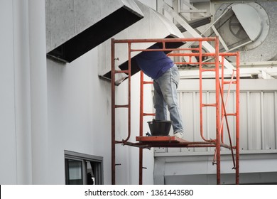 Worker Cleaning To Air Ventilation Of Factory. Man Standing On Steel Scaffolding For Cleaning Duct And Ventilation System In Factory Site.