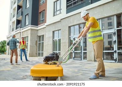 Worker Cleaning Construction Site And Two Men Near Building