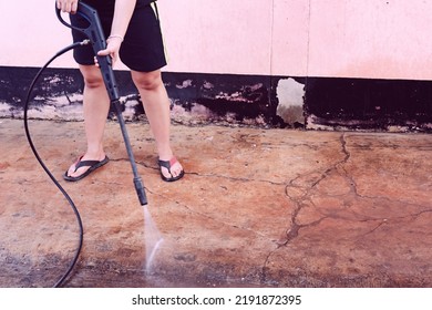 Worker Cleaning Dirty Floor With High Pressure Washer
