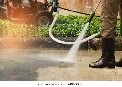 Worker cleaning driveway with gasoline high pressure washer splashing the dirt,professional cleaning services.High pressure cleaning,lower body. - Shutterstock ID 749500585