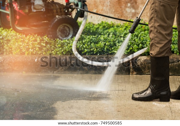 Worker cleaning driveway with gasoline high\
pressure washer splashing the dirt,professional cleaning\
services.High pressure cleaning,lower\
body.