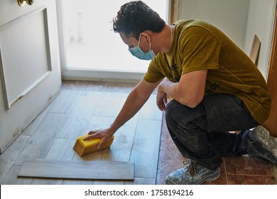 Worker Cleaning The Floor With A Sponge And Protective Mask Next To A Door