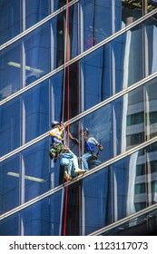  Worker cleaning glass wall of hi-rise building with his beautiful reflected and safety equipment 