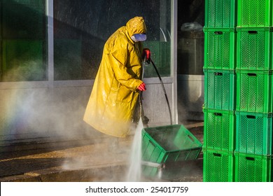 Worker cleaning green boxes in yellow safety protective equipment - Powered by Shutterstock