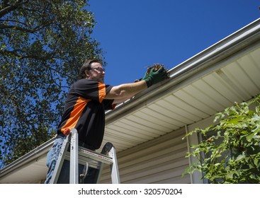 Worker Cleaning Gutters On A Customers Home.