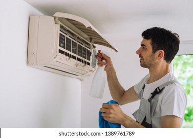 Worker Cleaning Home Air Conditioner With Antibacterial Spray