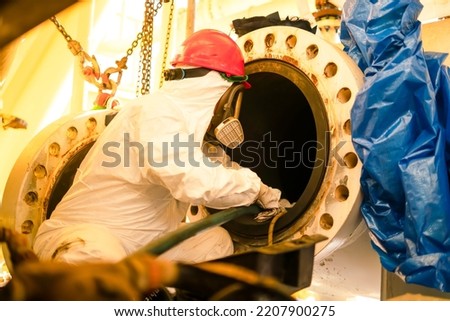 Worker cleaning internal pressure vessel in confine space.