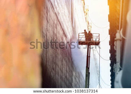 worker cleaning with ship by high pressure water ware equipment safety  harness for high work  under ship repair in floating dock minimal  monochrome concept with sun shines