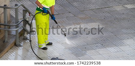 Worker cleaning a street sidewalk with high pressure water jet. Urban maintenance concept. Copy space