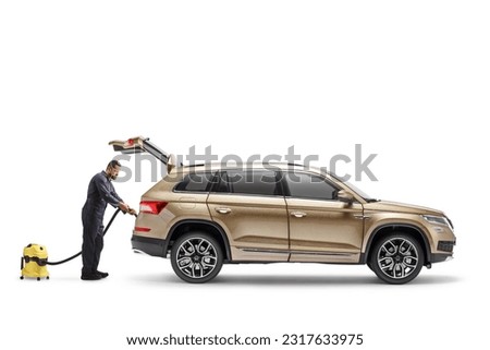 Worker cleaning a SUV with a vacuum cleaner isolated on white background