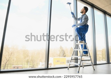 worker cleaning windows service on high rise building.