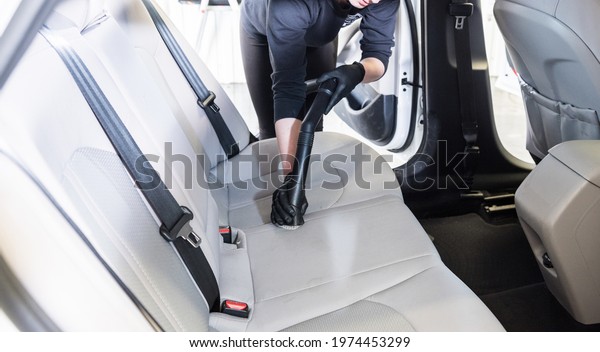 Worker cleans car
interior with vacuum
cleaner