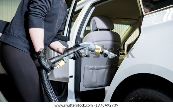 Worker cleans car\
interior with vacuum\
cleaner