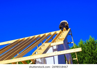 Worker is climbing framework of joists roofing adding rafters to roof