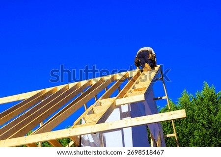 Worker is climbing framework of joists roofing adding rafters to roof
