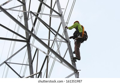 Worker Climbing On Transmission Line Tower