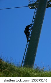 A Worker Climbing A Pole Of A Ski Lift