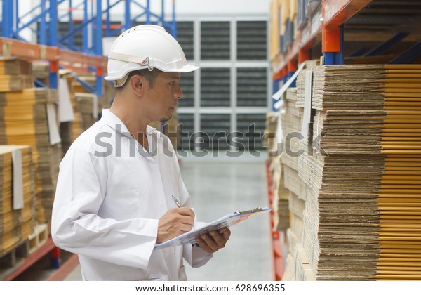 worker with clipboard in\
warehouse