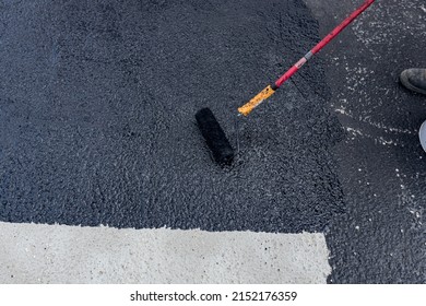 Worker Is Coating Tarmac Using A Brush Roller, Apply The First Basic Protective Layer Of Waterproofing.