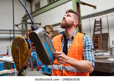 Worker at the control panel of a coordinate drilling machine in the workshop of a factory