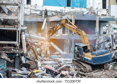 Worker controlling backhoe demolishing old buildings. Demolition site with pile of rubble and bulldozer at Bangkok site.