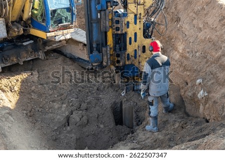 A worker controls the extraction of Larssen sheet piling from the ground after excavation work is completed at great depth.