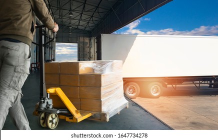 Worker Courier Unloading Cargo Pallet Shipment Goods, His Using Hand Pallet  Jack Load Into A Truck, Road Freight Transport, Warehouse Industrial Delivery Shipment  And Logistics