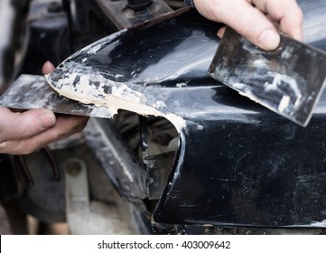 Worker cover car dents with filler material (putty) by metal spatula. Car repairing service. - Shutterstock ID 403009642