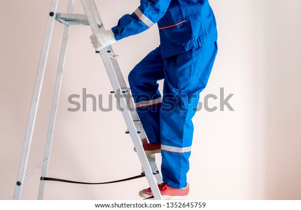 worker\
craftsman step up the ladder to repair home\

