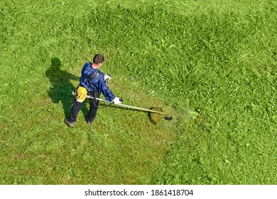 Arbeiter schneidet grünes Gras mit Rasenmäher, Draufsicht