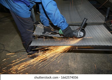 A worker cuts an iron mesh netting with an iron circle in a locksmith's workshop. Sparks fly - Powered by Shutterstock