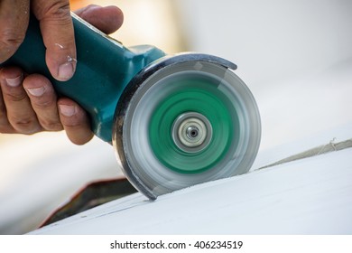 worker cutting ceiling with angle grinder in construction site