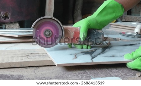 Worker cutting ceramic tile with angle grinder. Construction detail photo for renovation, flooring, and home improvement projects