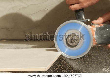 Worker cutting ceramic tile with disc grinder machine. DIY home improvement project.	